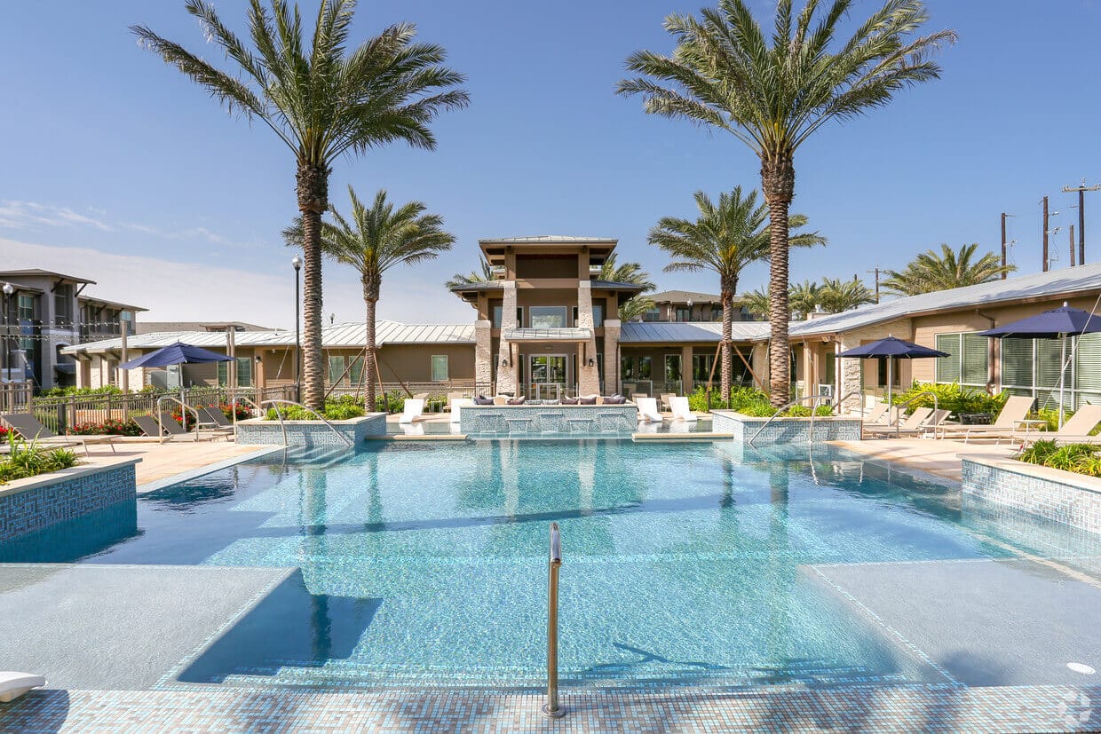 The pool area at Dalian 151, featuring a sparkling pool, lounge chairs, umbrellas, and lush landscaping, providing residents with a refreshing and relaxing outdoor retreat