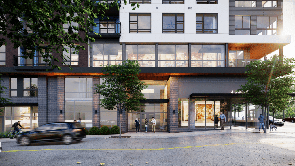 A modern building with people gathered outside and a car passing by in the foreground.